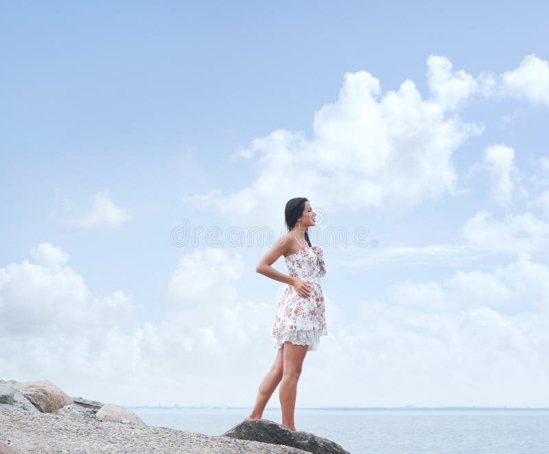 Uma jovem mulher em um vestido em um fundo do mar imagem de stock Uma jovem mulher em um vestido em um fundo do mar imagem de stock