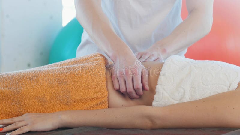 Uma jovem mulher que recebe uma massagem Um massagista que faz massagens o estômago fotos de stock Uma jovem mulher que recebe uma massagem Um massagista que faz massagens o estômago fotos de stock