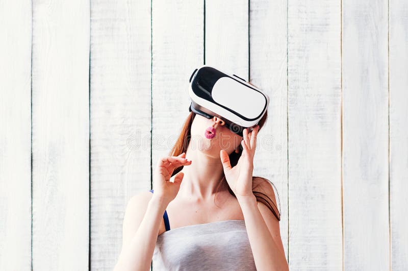 Uma jovem mulher que veste os vidros de VR, guardando suas mãos na cara, whi foto de stock royalty free Uma jovem mulher que veste os vidros de VR, guardando suas mãos na cara, whi foto de stock royalty free