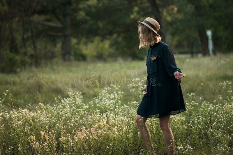 Uma menina bonita está andando ao longo do campo de flor imagens de stock Uma menina bonita está andando ao longo do campo de flor imagens de stock