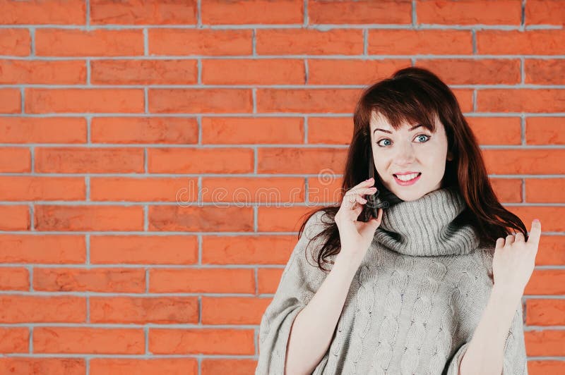 Uma menina bonita que fala pelo telefone celular, sorrindo surpreendentemente, em um g foto de stock Uma menina bonita que fala pelo telefone celular, sorrindo surpreendentemente, em um g foto de stock