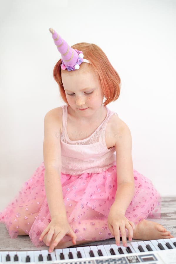 Uma menina em um vestido esperto joga o piano foto de stock royalty free Uma menina em um vestido esperto joga o piano foto de stock royalty free