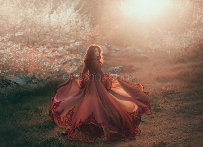 Uma menina moreno com cabelo ondulado, grosso corre ao sol e olha para trás A princesa tem um vestido luxuoso, chiffon, vermelho