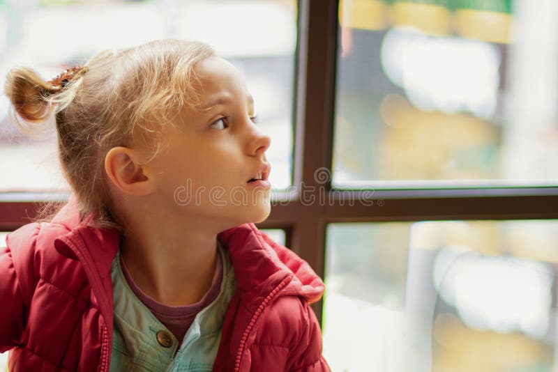 Uma menina olha ao lado pela janela fotos de stock royalty free Uma menina olha ao lado pela janela fotos de stock royalty free