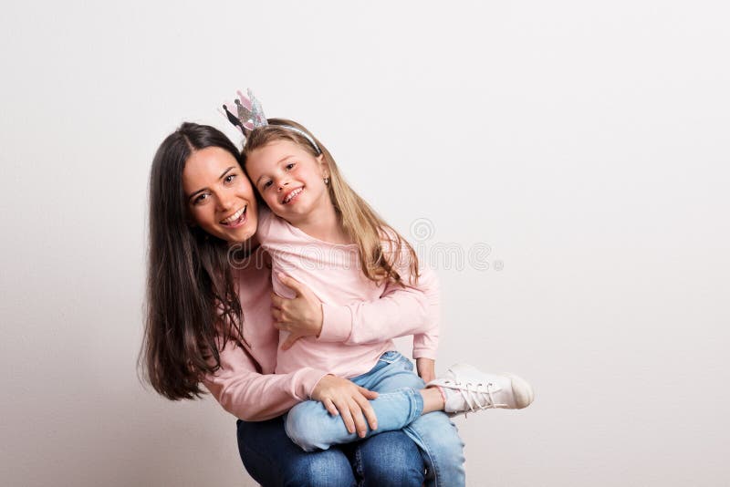 Uma menina pequena com faixa da coroa e sua mãe que senta-se em um estúdio fotos de stock royalty free Uma menina pequena com faixa da coroa e sua mãe que senta-se em um estúdio fotos de stock royalty free