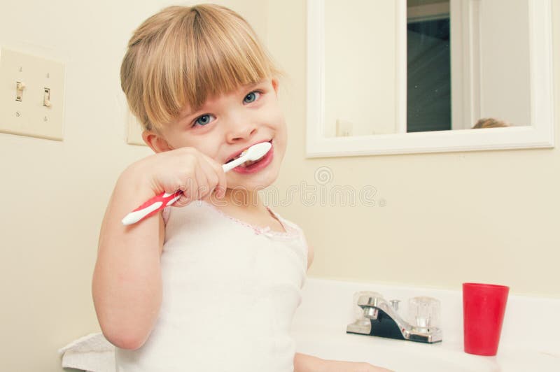 Uma menina que escova seus dentes fotos de stock royalty free Uma menina que escova seus dentes fotos de stock royalty free