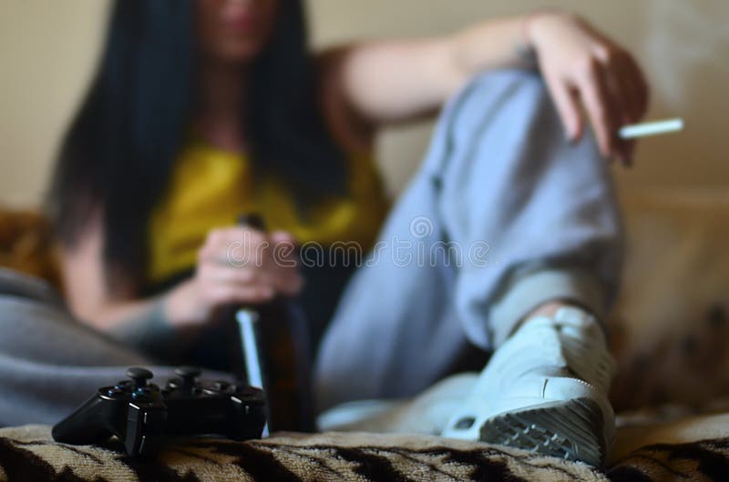 Uma menina que senta-se no sofá, fumando um cigarro, cerveja bebendo fotos de stock royalty free Uma menina que senta-se no sofá, fumando um cigarro, cerveja bebendo fotos de stock royalty free
