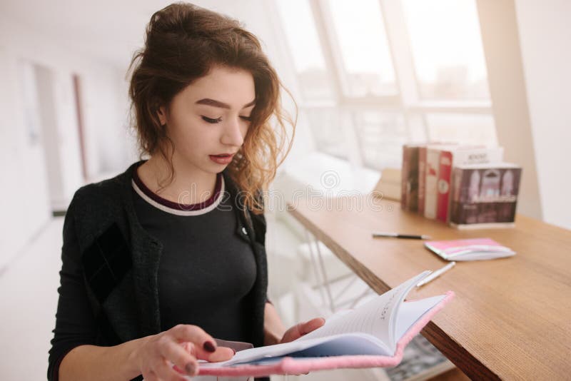 Uma menina é de assento e de leitura um caderno fotos de stock Uma menina é de assento e de leitura um caderno fotos de stock