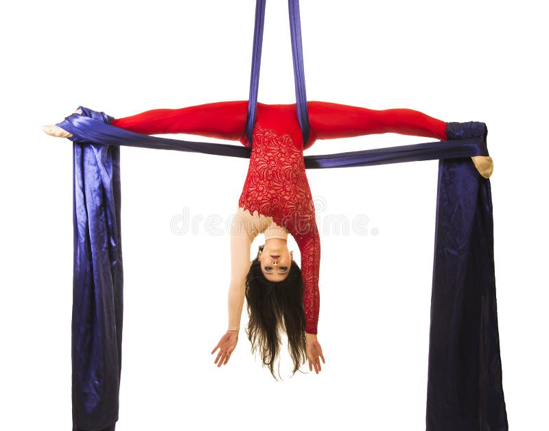 Uma moça com cabelo longo em um terno vermelho executa exercícios ginásticos e do circo na seda fotografia de stock royalty free
