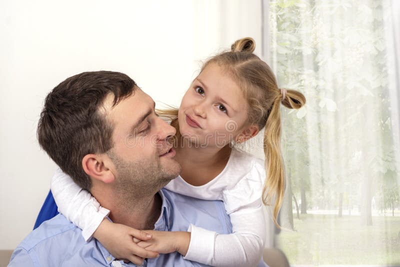 Uma moça que abraça seu pai com uma expressão feliz foto de stock royalty free Uma moça que abraça seu pai com uma expressão feliz foto de stock royalty free