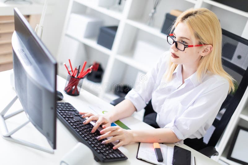 Uma moça que trabalha em um computador no escritório imagem de stock royalty free Uma moça que trabalha em um computador no escritório imagem de stock royalty free