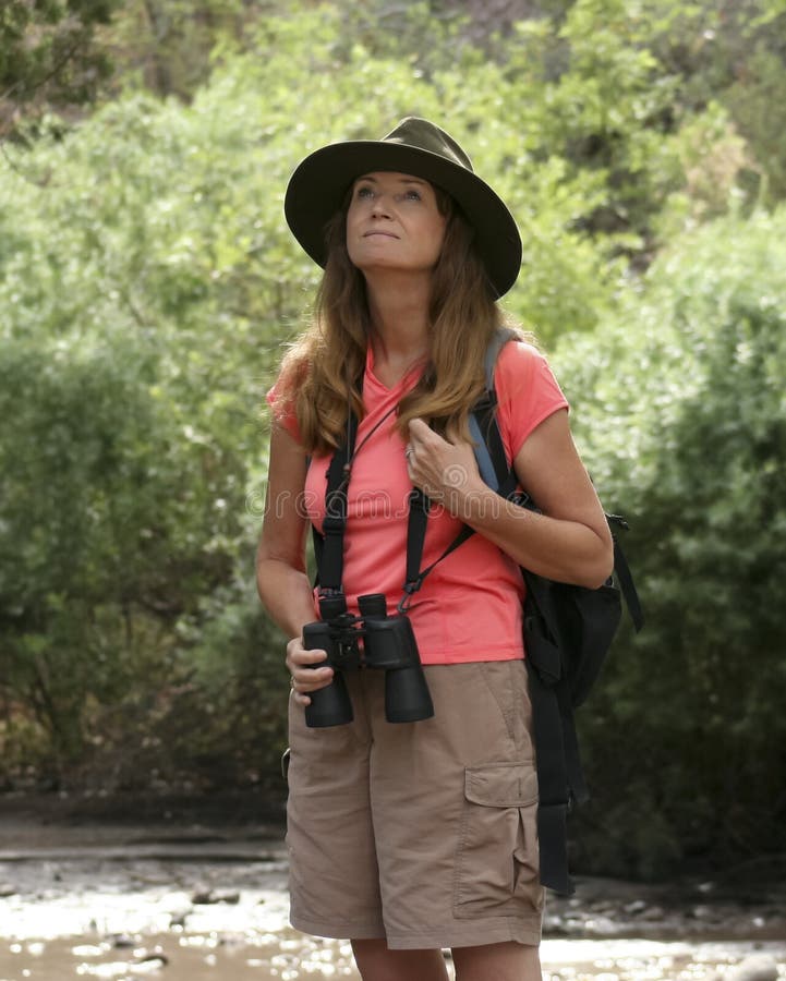 Uma mulher atrativa que Birdwatching por um rio fotografia de stock royalty free Uma mulher atrativa que Birdwatching por um rio fotografia de stock royalty free