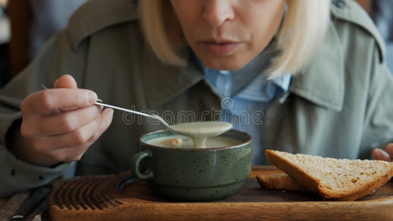 Uma mulher comendo sopa deliciosa em um restaurante. prato quente preparado profissionalmente.