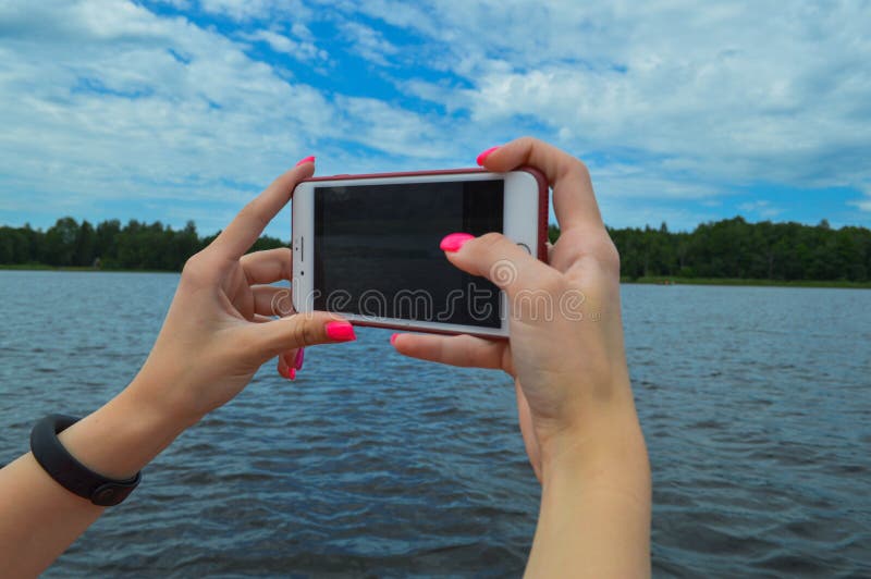 Uma mulher da menina com realizar alaranjados cor-de-rosa do tratamento de mãos bonito dos pregos em suas mãos um smartphone do t foto de stock royalty free Uma mulher da menina com realizar alaranjados cor-de-rosa do tratamento de mãos bonito dos pregos em suas mãos um smartphone do t foto de stock royalty free