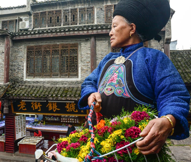 Uma mulher de Miao que vende flores na cidade antiga de Fenghuang em Hunan, China fotografia de stock royalty free Uma mulher de Miao que vende flores na cidade antiga de Fenghuang em Hunan, China fotografia de stock royalty free