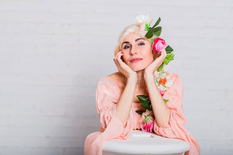 Uma mulher de ninhada bonita dobrou suas mãos sob seu queixo flores artificiais em seu cabelo fotos de stock Uma mulher de ninhada bonita dobrou suas mãos sob seu queixo flores artificiais em seu cabelo fotos de stock
