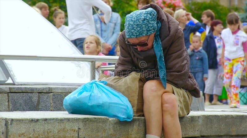 Uma mulher desabrigada bêbado está sentando-se na rua, ondulada acima vídeos de arquivo