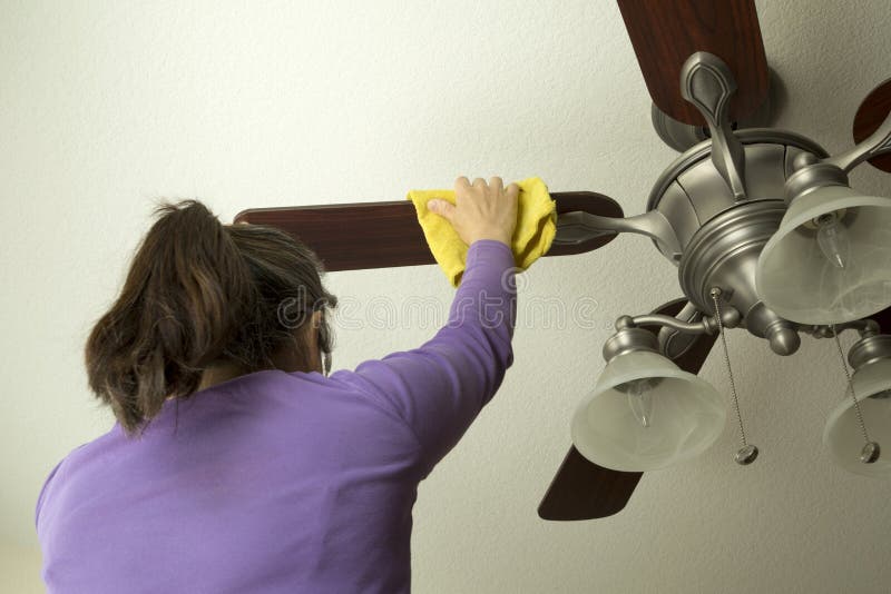 Uma mulher está limpando o fã de teto