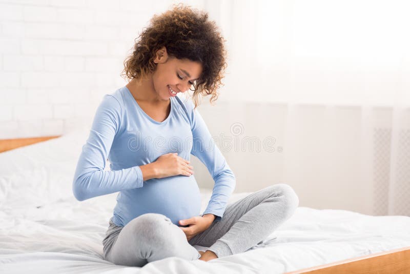Uma mulher grávida a acariciar a barriga, a falar com o bebê
