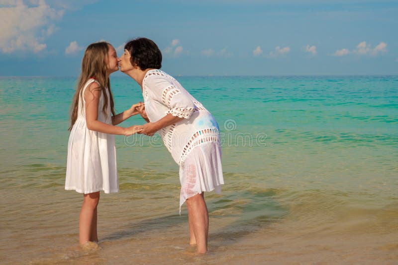 Uma mulher idosa e uma menina bonita na praia A avó beija sua neta em um dia ensolarado Conceito do amor e da fam?lia fotos de stock royalty free Uma mulher idosa e uma menina bonita na praia A avó beija sua neta em um dia ensolarado Conceito do amor e da fam?lia fotos de stock royalty free