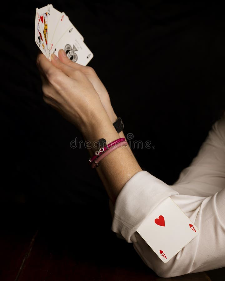 A young woman plays poker with an ace of hearts tucked into the cuff of her white shirt. A young woman plays poker with an ace of hearts tucked into the cuff of her white shirt