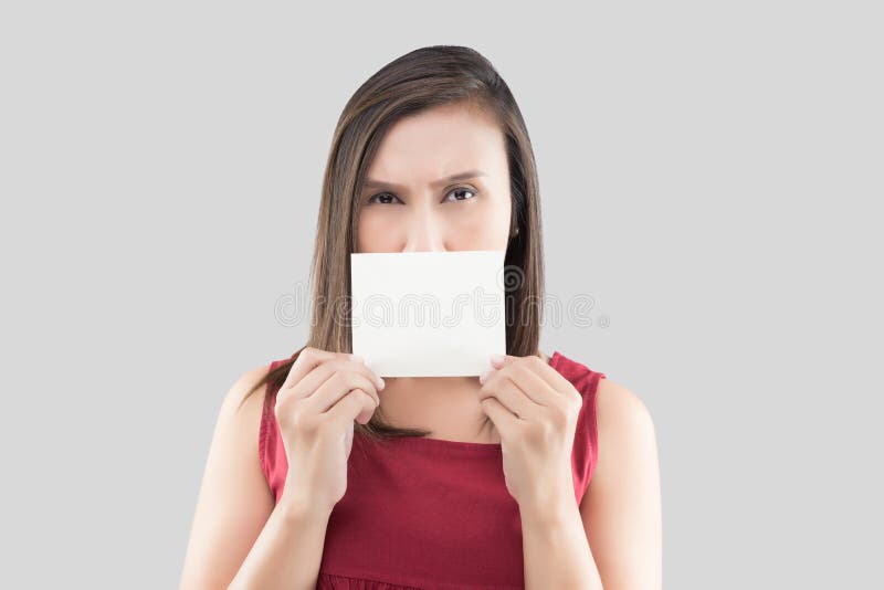 Uma mulher na camisa vermelha que mantém o cartão branco vazio com espaço para o texto na frente de sua boca contra o fundo cinze fotos de stock royalty free Uma mulher na camisa vermelha que mantém o cartão branco vazio com espaço para o texto na frente de sua boca contra o fundo cinze fotos de stock royalty free