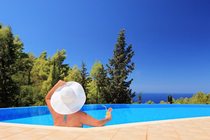 Uma mulher que relaxa em uma piscina com cocktail fotografia de stock Uma mulher que relaxa em uma piscina com cocktail fotografia de stock