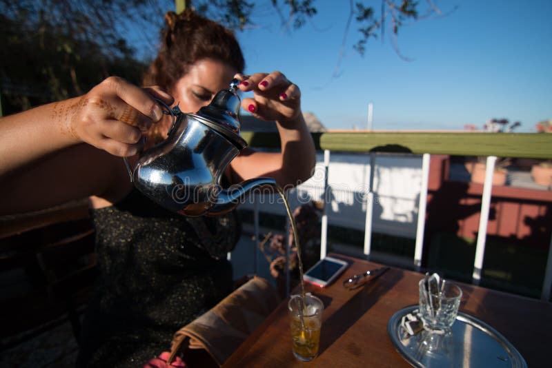 Uma mulher que serve o chá tradicionalmente no terraço de um café em C4marraquexe, Marrocos imagem de stock Uma mulher que serve o chá tradicionalmente no terraço de um café em C4marraquexe, Marrocos imagem de stock