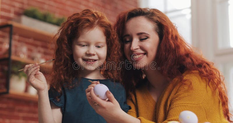 Uma mãe e seus ovos da páscoa de pintura da filha na cozinha acolhedor Eles que riem e para ter o divertimento Família feliz que fotografia de stock Uma mãe e seus ovos da páscoa de pintura da filha na cozinha acolhedor Eles que riem e para ter o divertimento Família feliz que fotografia de stock