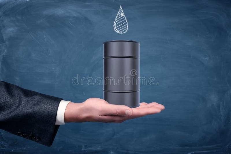 Uma mão do ` s do homem de negócios girada acima e um tambor de óleo preto pequeno que está nele com uma gota tirada no quadro foto de stock royalty free Uma mão do ` s do homem de negócios girada acima e um tambor de óleo preto pequeno que está nele com uma gota tirada no quadro foto de stock royalty free