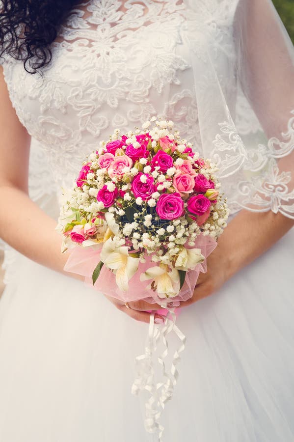 Uma noiva em um vestido de casamento branco está guardando um ramalhete em suas mãos Close-up, foco seletivo Tonificação ao estil fotos de stock Uma noiva em um vestido de casamento branco está guardando um ramalhete em suas mãos Close-up, foco seletivo Tonificação ao estil fotos de stock