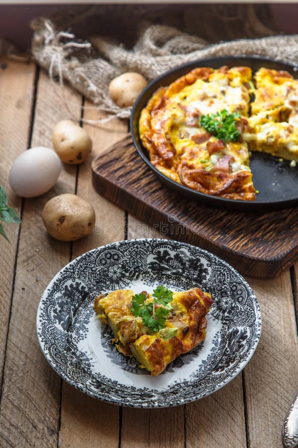 Uma parte de francês cozeu o couve-de-milão da omeleta com presunto, queijo, batata e alho-porro em uma placa, estilo rústico, vi foto de stock royalty free Uma parte de francês cozeu o couve-de-milão da omeleta com presunto, queijo, batata e alho-porro em uma placa, estilo rústico, vi foto de stock royalty free