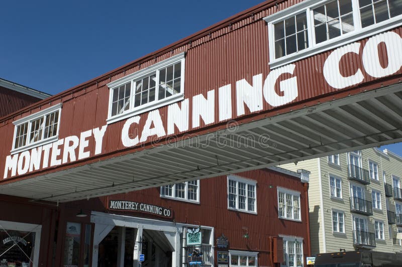 An overhead walkway advertising Monterey Canning Company crosses over Cannery Row. An overhead walkway advertising Monterey Canning Company crosses over Cannery Row.