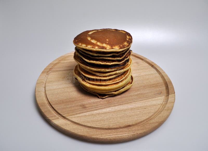 Uma pilha de panquecas douradas redondas em um suporte de madeira imagem de stock Uma pilha de panquecas douradas redondas em um suporte de madeira imagem de stock