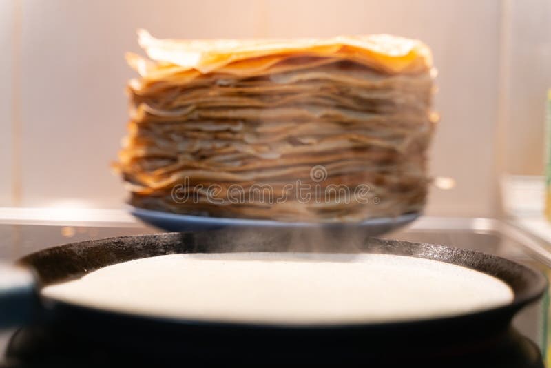 Uma pilha de panquecas fritadas pré-feitos as panquecas são fritadas em uma frigideira preta imagem de stock Uma pilha de panquecas fritadas pré-feitos as panquecas são fritadas em uma frigideira preta imagem de stock