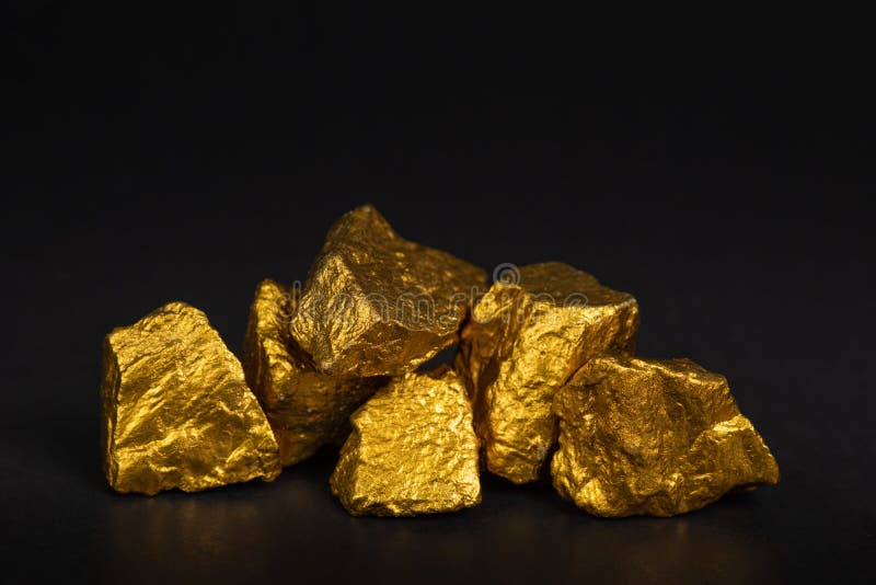 Uma pilha de pepitas de ouro ou de minério do ouro no fundo preto, muito