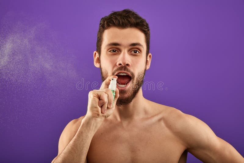 Uma respiração de pulverização do homem considerável para refrescar sua boca imagens de stock royalty free Uma respiração de pulverização do homem considerável para refrescar sua boca imagens de stock royalty free