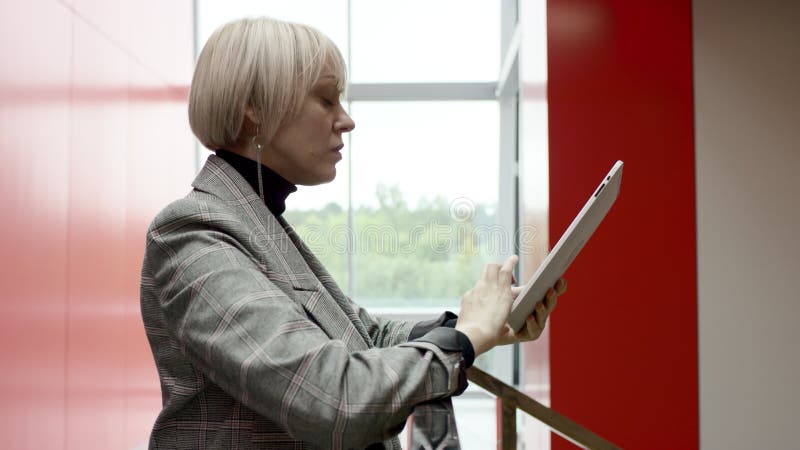 Uma vista lateral em câmera lenta fechar uma mulher de negócios em um casaco cinza procurando um artigo online para ler sobre ela