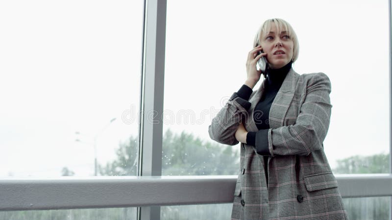Uma visão lateral em câmera lenta fechar uma jovem loira empresária discutindo um tópico com seu colega ao telefone
