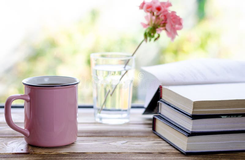 A pink cup with tea stands on a wooden windowsill next to books and a glass in which stands a pink geranium flower, against the background of a summer garden, drink, hot, morning, home, white, room, reading, relax, vintage, mug, weather, mood, interior, fresh, house, rest, view, warm, calm, comfort, rustic, season, space, concept, design, beverage, free, moody, weekend, copy, frame, indoors, leisure, break, bouquet, desk. A pink cup with tea stands on a wooden windowsill next to books and a glass in which stands a pink geranium flower, against the background of a summer garden, drink, hot, morning, home, white, room, reading, relax, vintage, mug, weather, mood, interior, fresh, house, rest, view, warm, calm, comfort, rustic, season, space, concept, design, beverage, free, moody, weekend, copy, frame, indoors, leisure, break, bouquet, desk