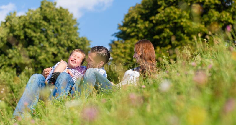 Umarmungsc$sitzen der Familie auf Wiese im Sommer stockbild Umarmungsc$sitzen der Familie auf Wiese im Sommer stockbild