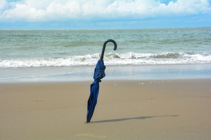 An Umbrella is Stuck in the Sand on the Beach in Sunlight Stock Image