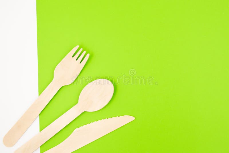 Öko-freundliche Einwegbesteck-Geräte auf grünem Hintergrund. Bambus Holzgabemesser und Löffel. lizenzfreie stockfotografie