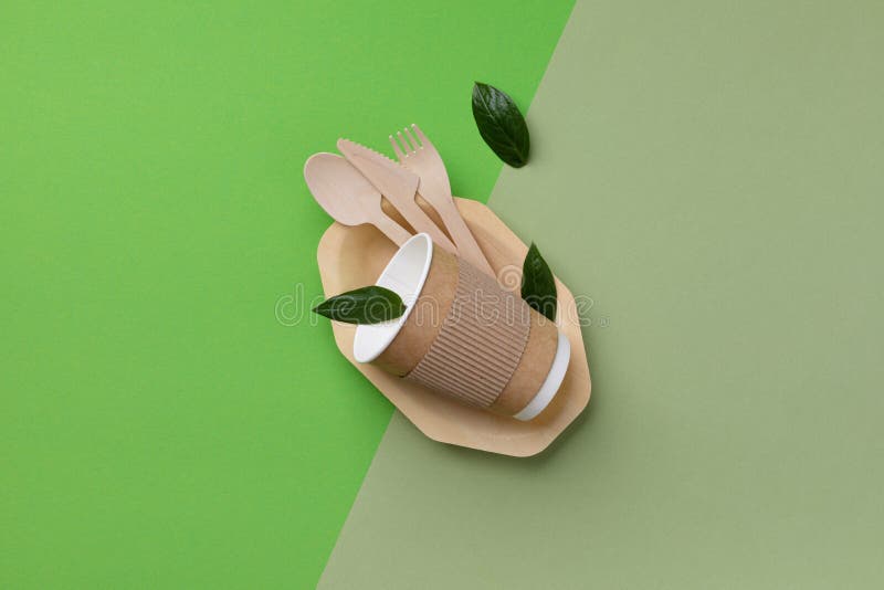 Umweltfreundliche Einwegtabellware auf grüner Hintergrundansicht. Nullabfall- und Kunststofffreie Minimalkonzeption lizenzfreie stockfotos