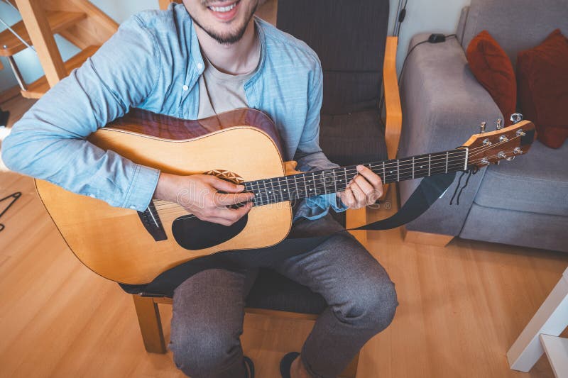 Un acercamiento a un músico en un acogedor hogar inmerso en la música. Su estilo casual iluminación cálida y relajado imagen de archivo