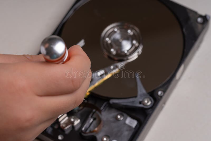 Un adolescente desmonta el disco duro de una computadora para estudiar su dispositivo imagen de archivo libre de regalías Un adolescente desmonta el disco duro de una computadora para estudiar su dispositivo imagen de archivo libre de regalías