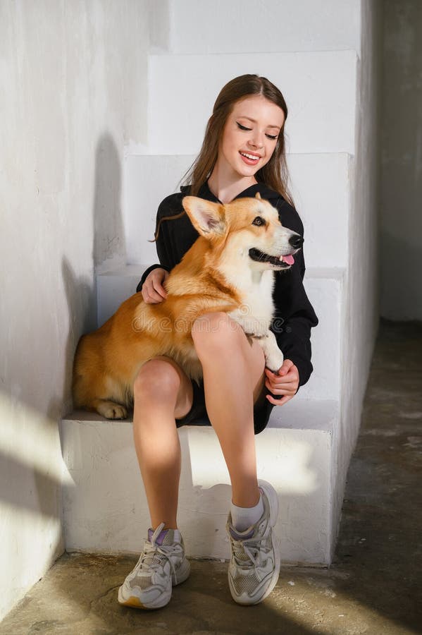 Un'adolescente siede con il suo cane da corgi fotografie stock libere da diritti