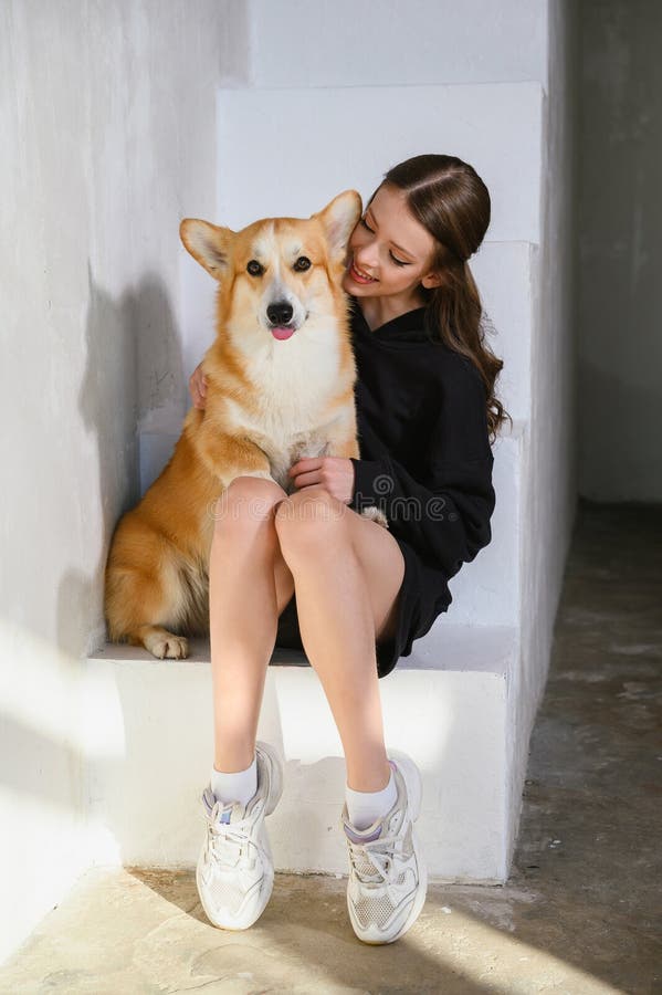 Un'adolescente siede con il suo cane da corgi immagini stock