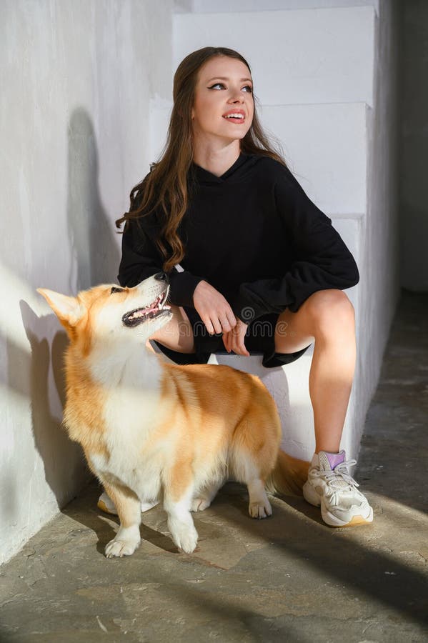 Un'adolescente siede con il suo cane da corgi fotografia stock libera da diritti
