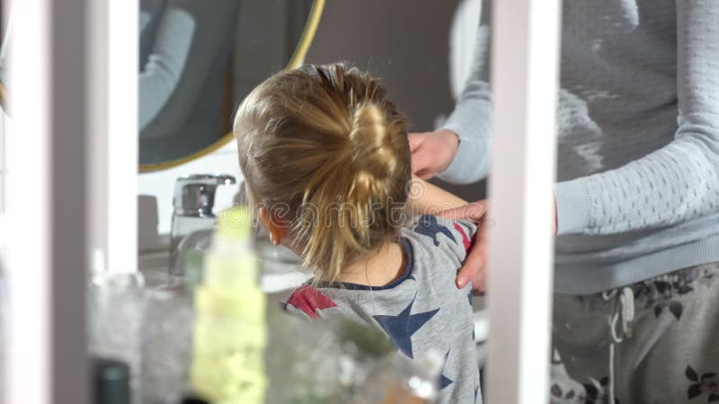 Un adulte aide un enfant à se brosser les dents dans un lavabo de salle de bain. banque de vidéos